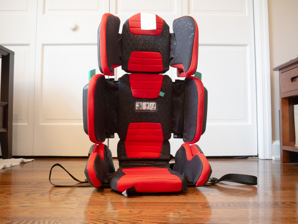 Travel Car Seat Mom - A red and black travel car seat on a wood floor.